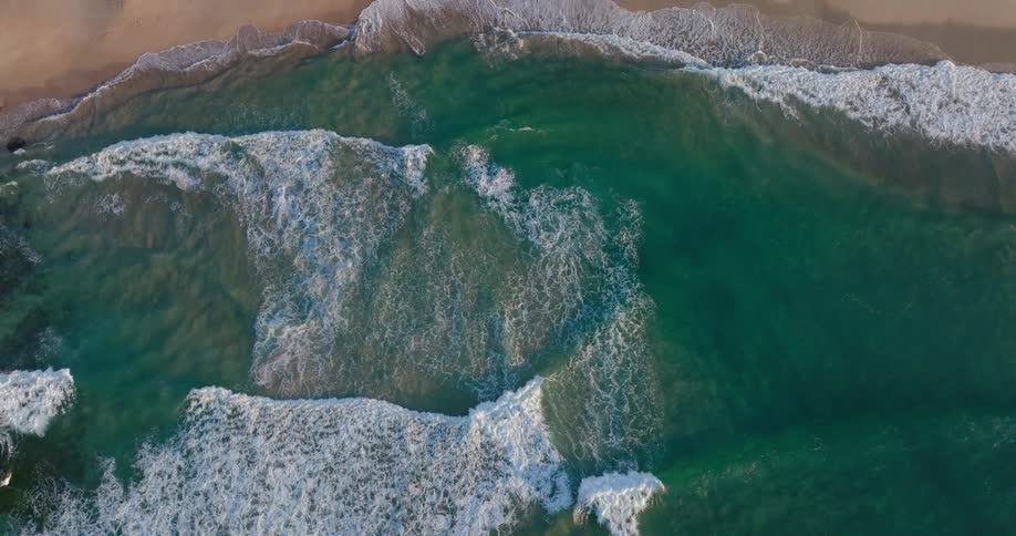 Aerial of waves crashing onto the shoreline on a sandy beach