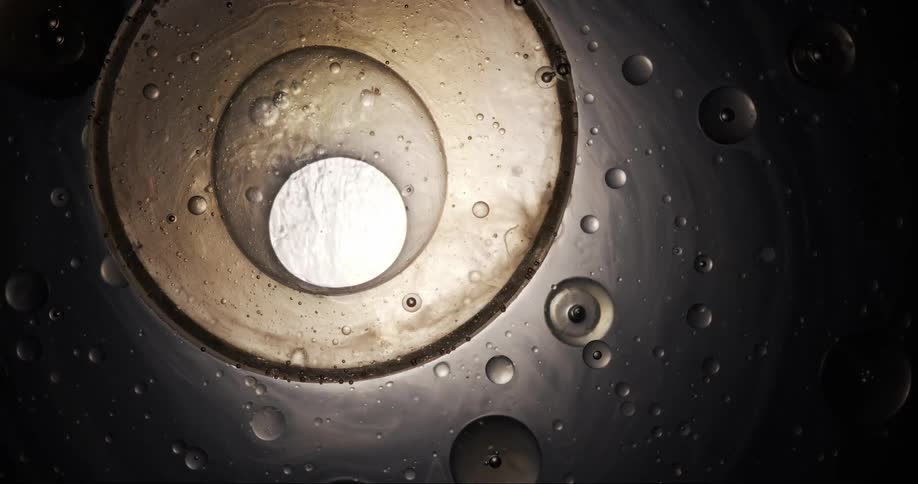 Air bubbles merge and pop floating on a thick and viscous liquid on a dark environment