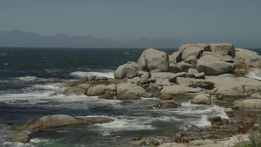 Large boulders and rocks on a beach head next to the ocean