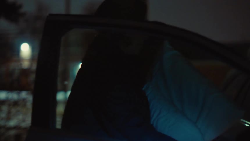 Woman puts cushion into the car on a cold night