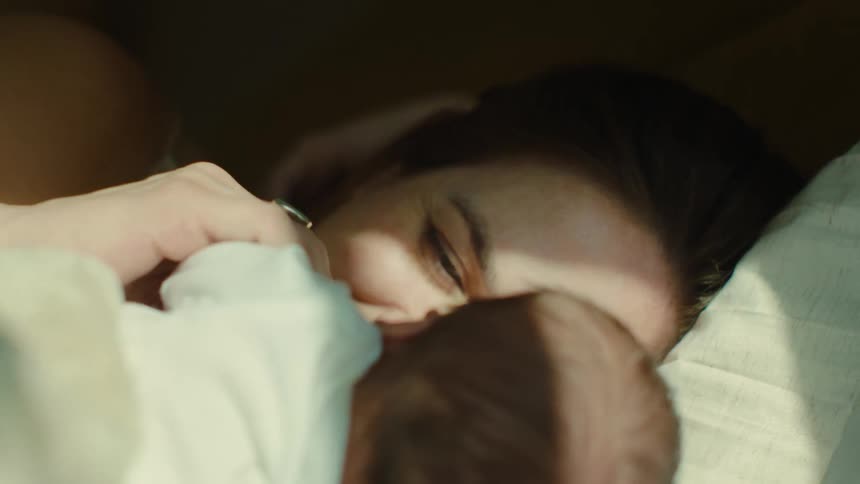 A woman is happily looking at her newborn baby who is in front of her