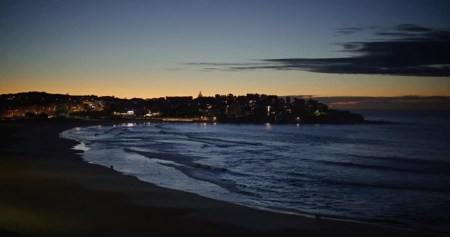 Waves gently rolling onto the shoreline on a beach with waterfront buildings nearby