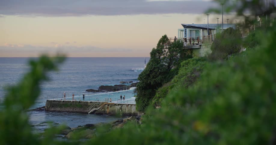 A small group of people are scattered outside of a beach house overlooking the ocean