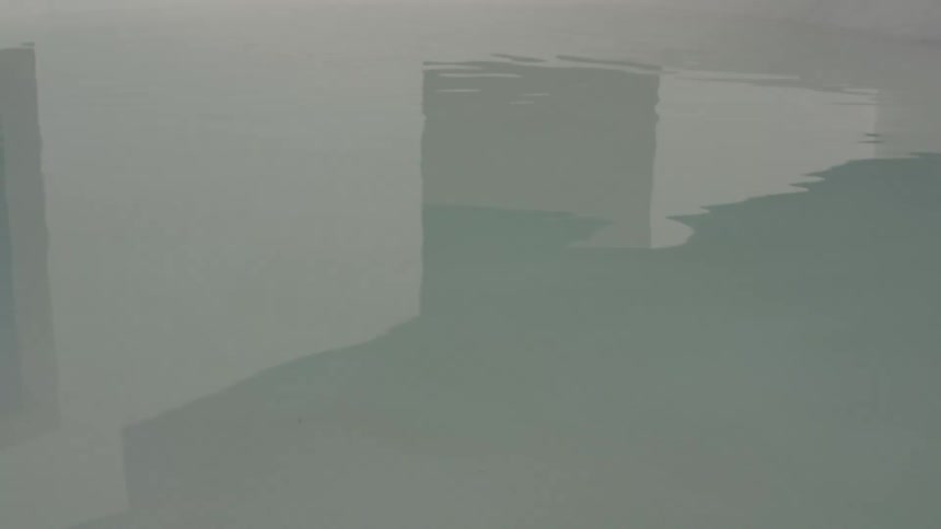Reflection of white buildings on the surface of calm water with small ripples