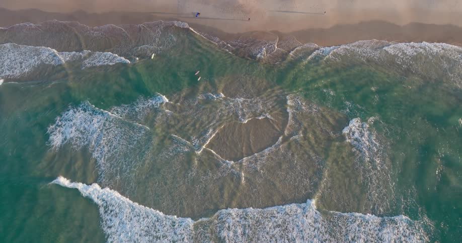 Aerial view of foamy waves crashing onto the beach sand