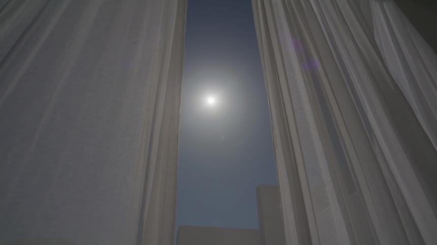 White curtain on a glass door against a sun on a clear day