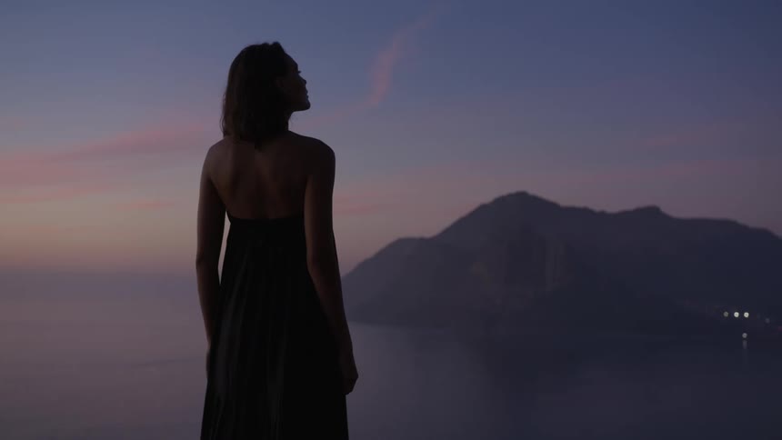 A woman stands overlooking the ocean