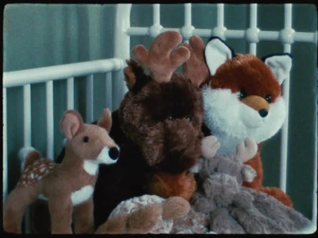 Stuffed animals piled in the corner of a white crib