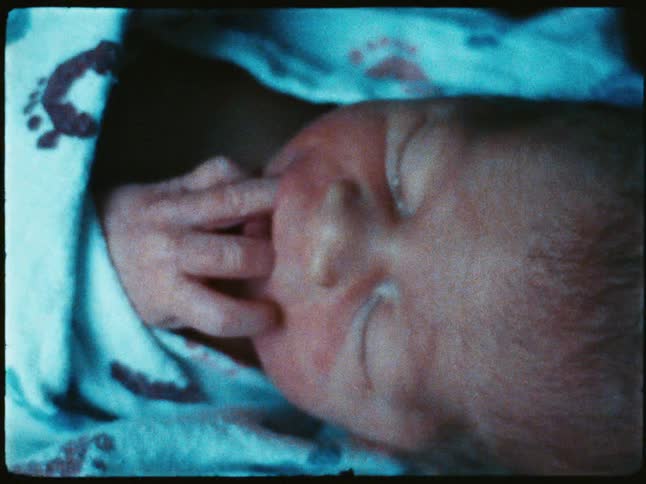Portrait of a newborn baby with fingers in mouth