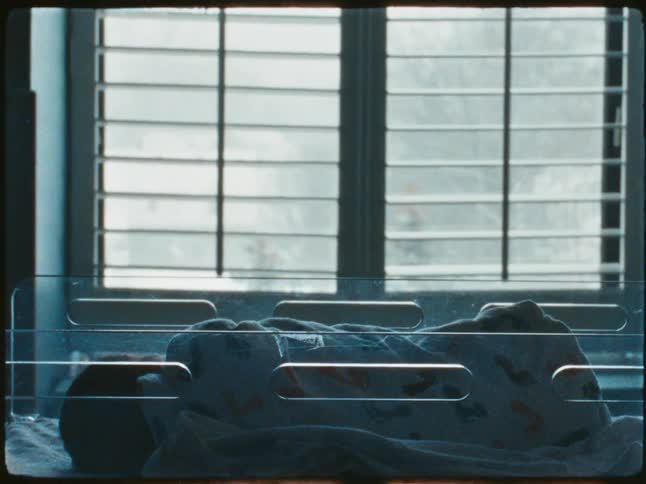 A baby asleep on a hospital crib caught on vintage film