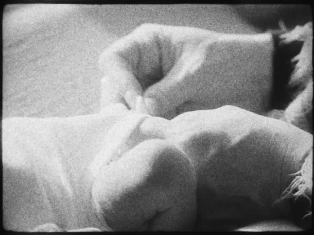 Pair of hands adjusting a newborn babys clothes