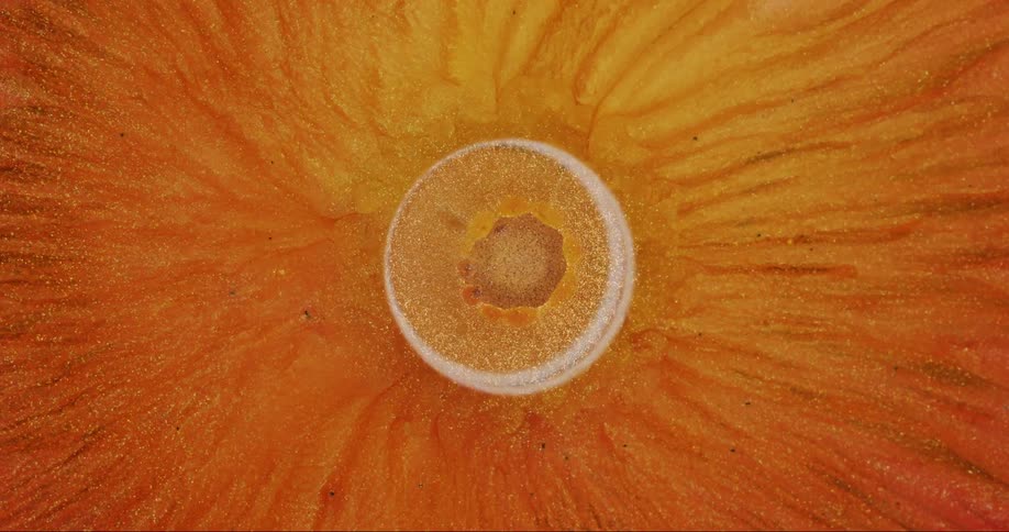 Streaks of glittering golden liquid flow from an expanding circle in the center