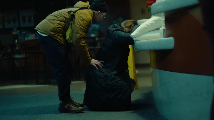 Man massaging the back of his wife who is crouched in the reception area of a hospital