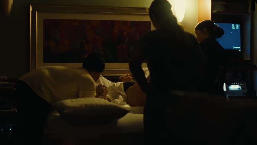 Man holding hands with his wife who is lying in a bed pregnant and two nurses beside her