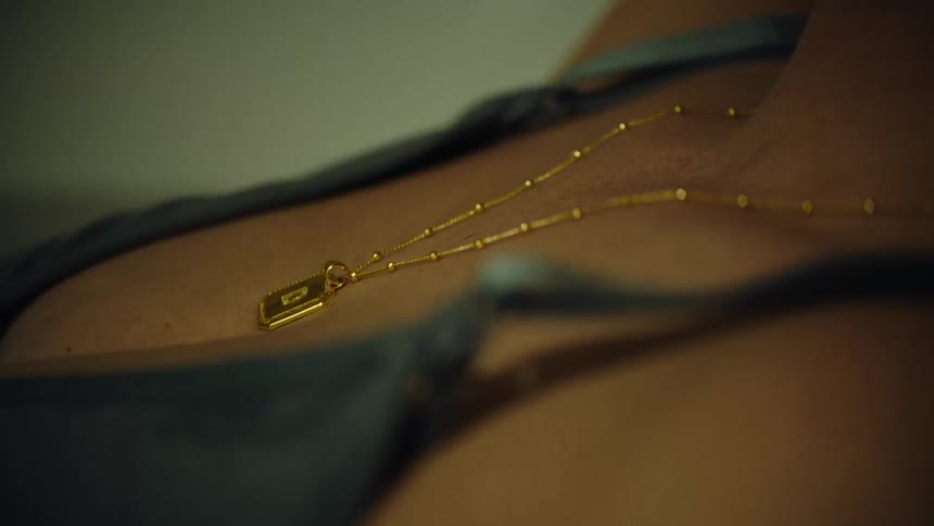 A closeup of a gold necklace on a persons chest