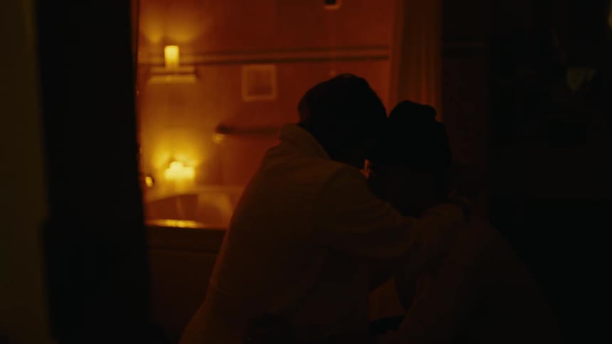 Couple hugging in a bathroom with lit candles