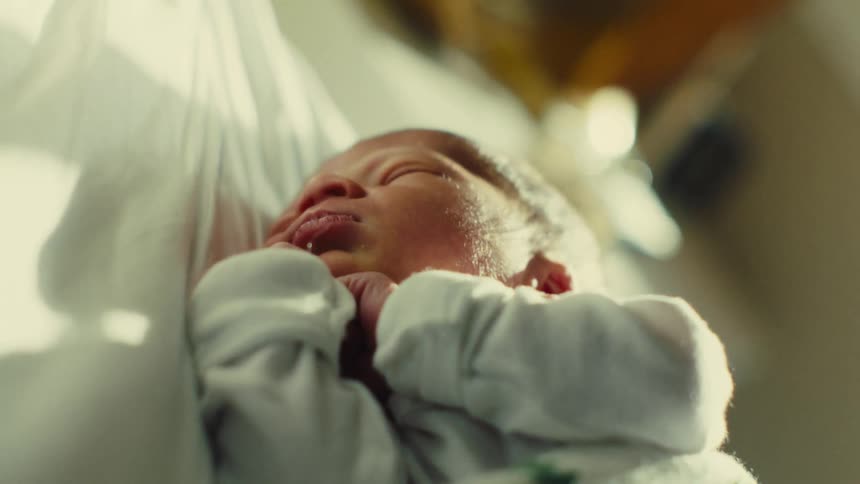 A newborn baby is sleeping and with his two hands under his chin