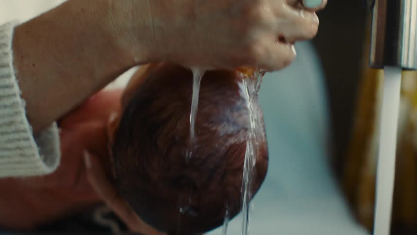 Hand wetting a loofah and giving a bath to a newborn baby