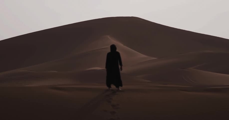 Person in burqa walking in the desert