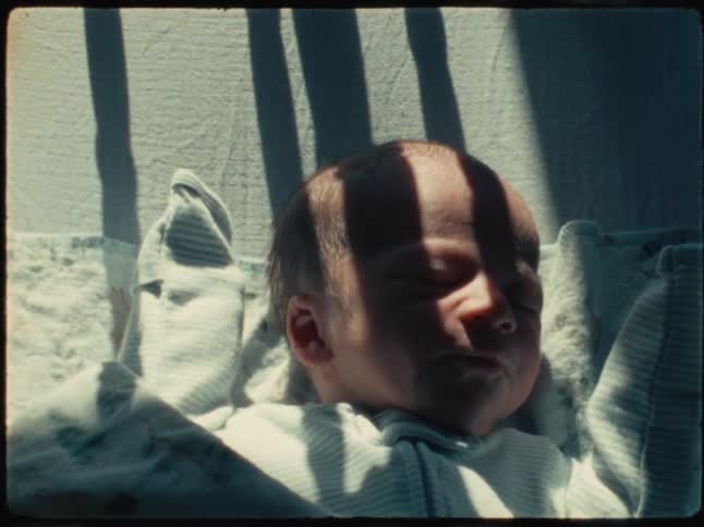 A sleeping baby tosses and turns in bed