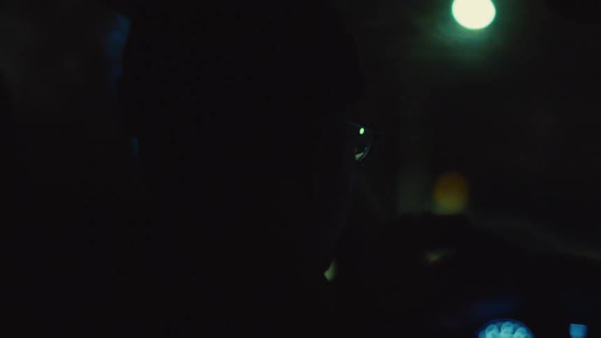 Side portrait of a man in a cap driving a car at night