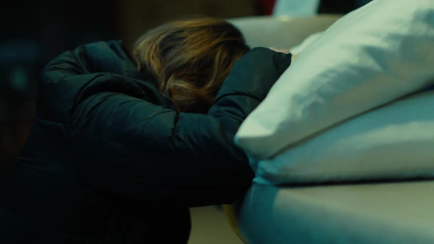 Woman crouched with her face and arms resting on a pillow