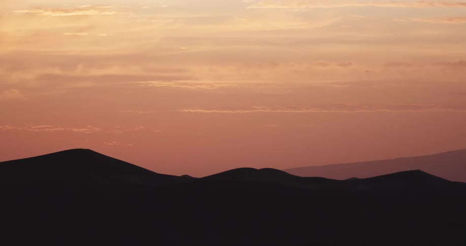 Silhouette of desert dunes against a reddish sky