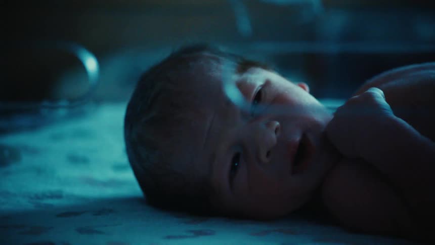 Newborn baby sleeps in a clear bassinet in the hospital at night