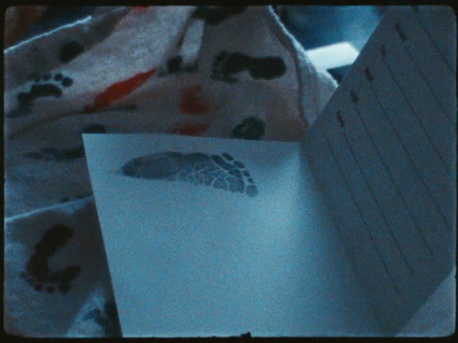 A closeup of a person holds a notebook with a baby feet imprint on it