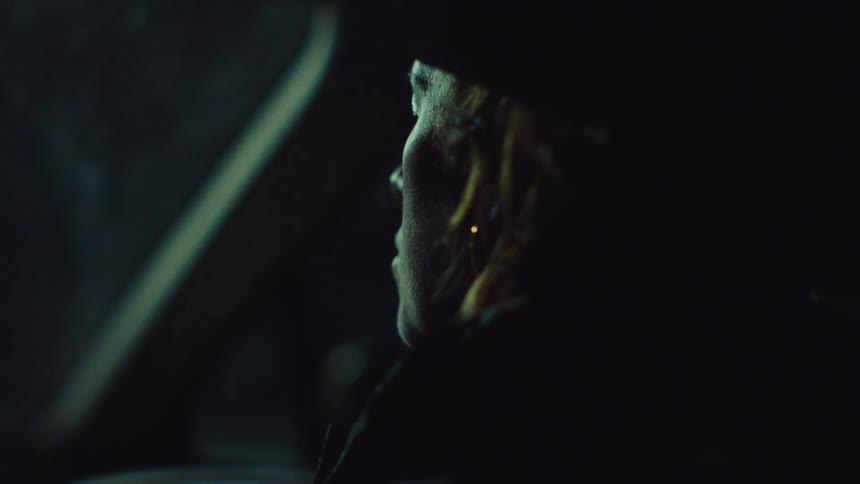 Person sitting in the front passenger seat of a car moving along the streets at night