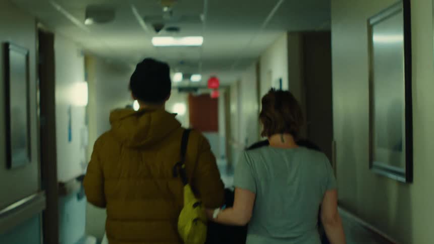 A couple locking arms walks down the hallway of a hospital