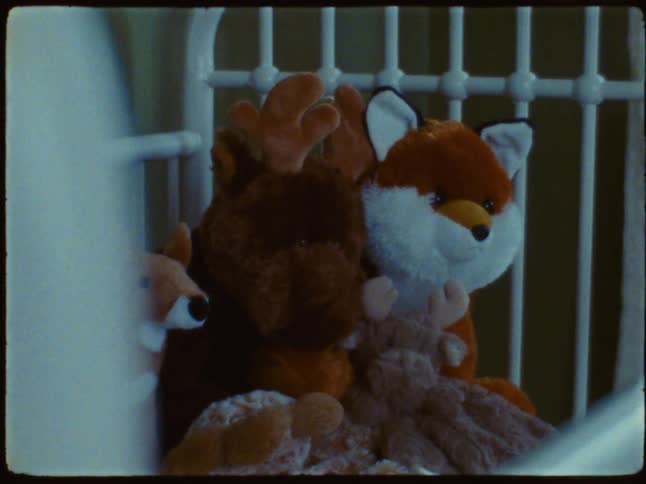 A collection of stuffed animals in a crib and clothes arranged in a wardrobe