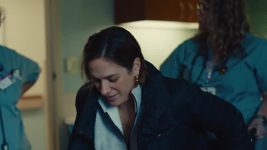Woman sitting in a chair in a hospital with nurses standing next to her
