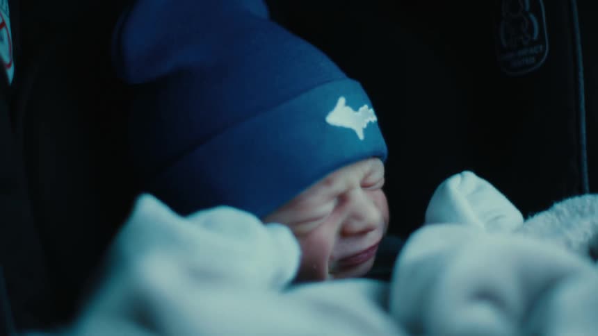 Portrait of a newborn baby with a cap and blanket