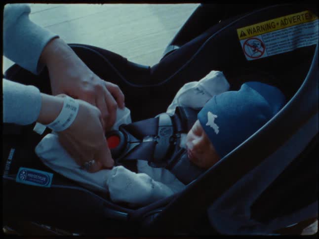 Mother arranging newborn baby in a mobile crib stroller