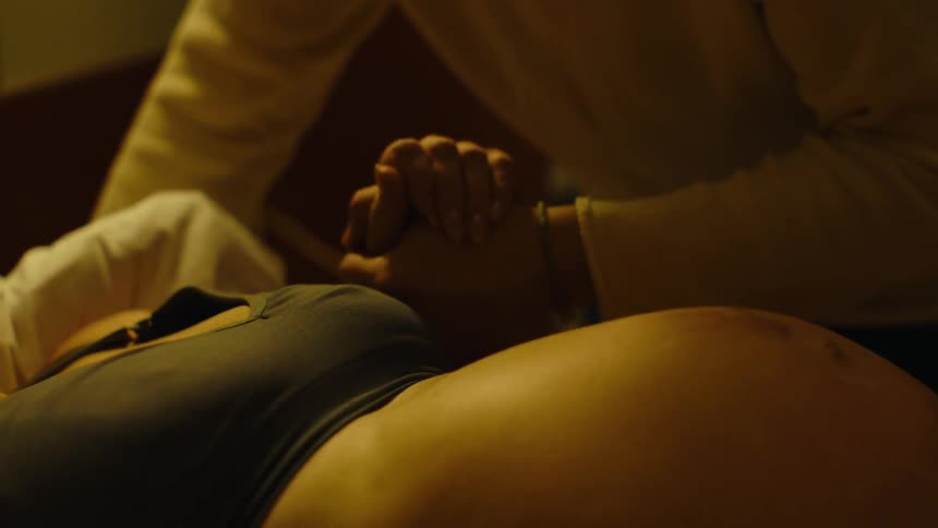 Two hands are clasped over a pregnant womans belly