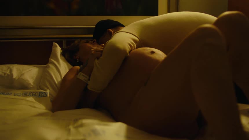 Man hugging his pregnant wife while she is lying in bed