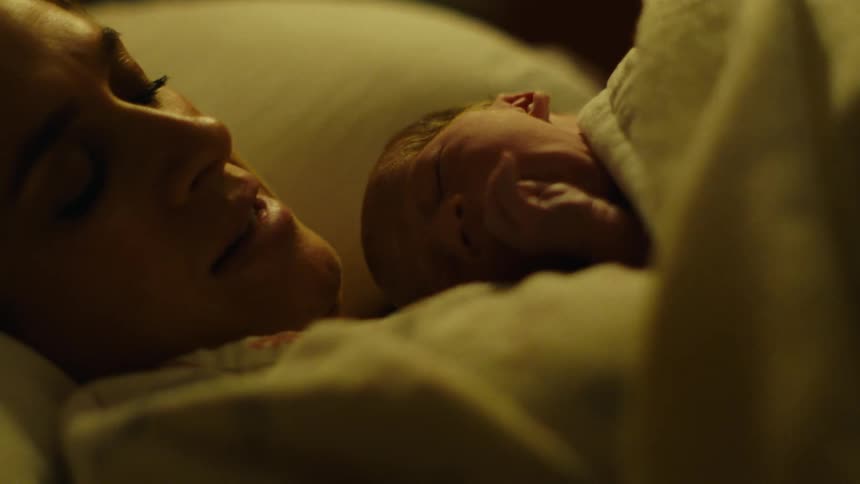 A mother lays in bed with her baby