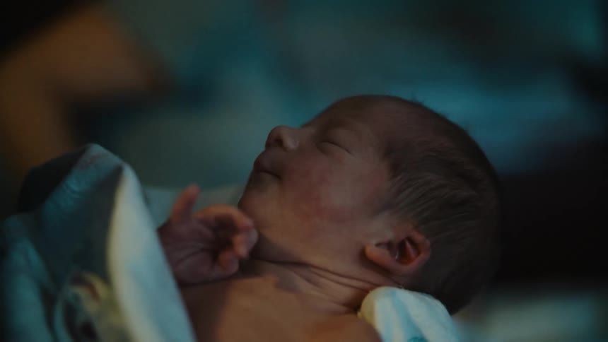 Portrait of a newborn baby on a persons lap