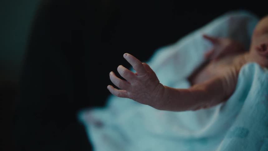 A closeup of a newborn babys hand reaching out