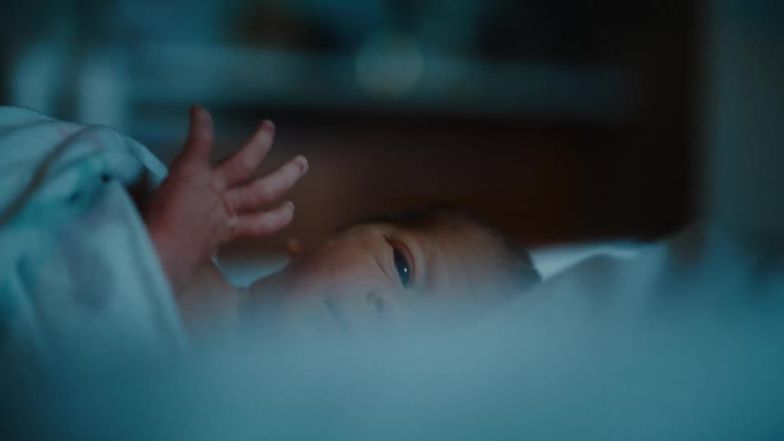 Portrait of a newborn baby moving his tiny hand while lying down