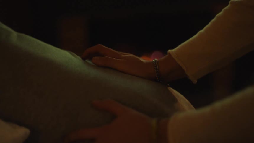 Closeup of a therapists hands gently massaging a client in front of a cozy fireplace