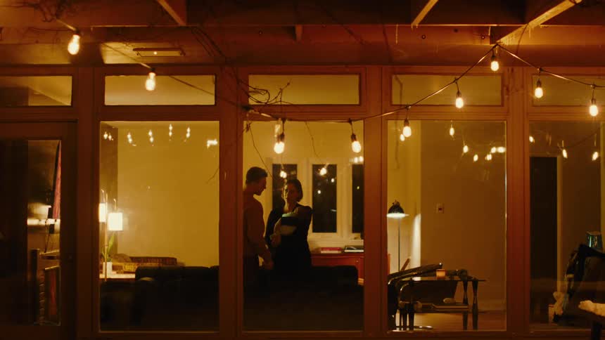 Mother holding baby on her lap next to father in a room at night