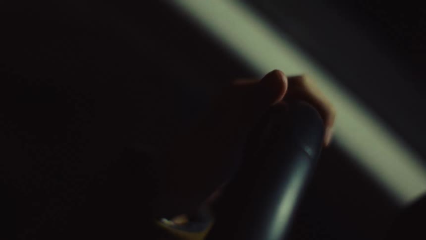 Hand on the steering wheel of a moving car at night