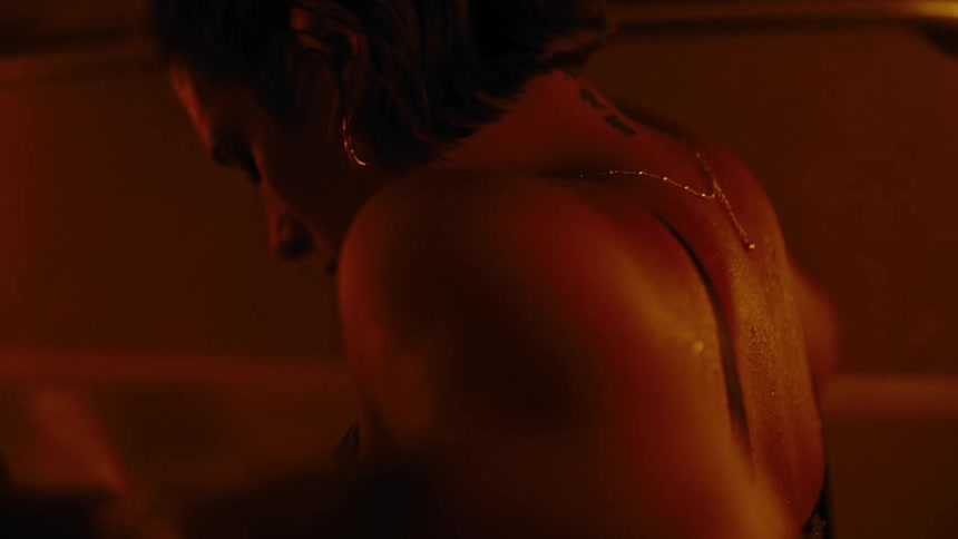 A woman is standing with her back turned and there is a strong orange light in the room