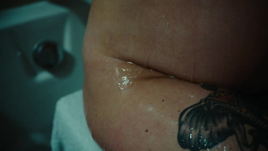 A waist of a person with a tattoo and there is water falling down the persons skin