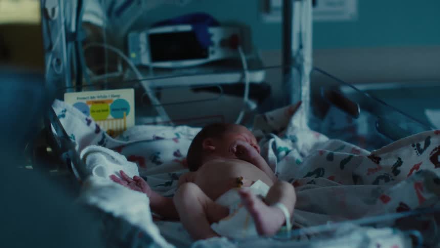 Newborn baby in hospital on a stretcher with machines and nurses next to it