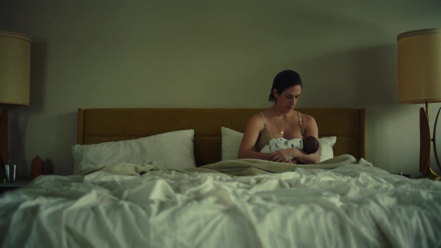 A woman sitting on a bed holding her baby