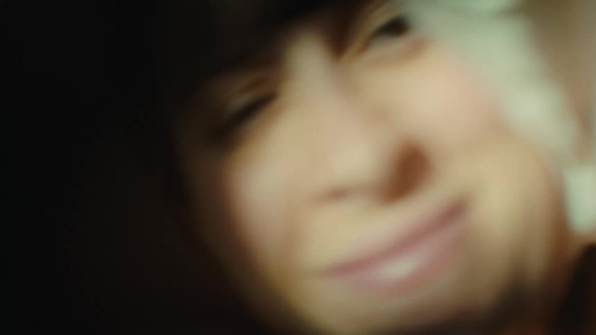 Blurred closeup of a womans smiling face gazing directly at the camera