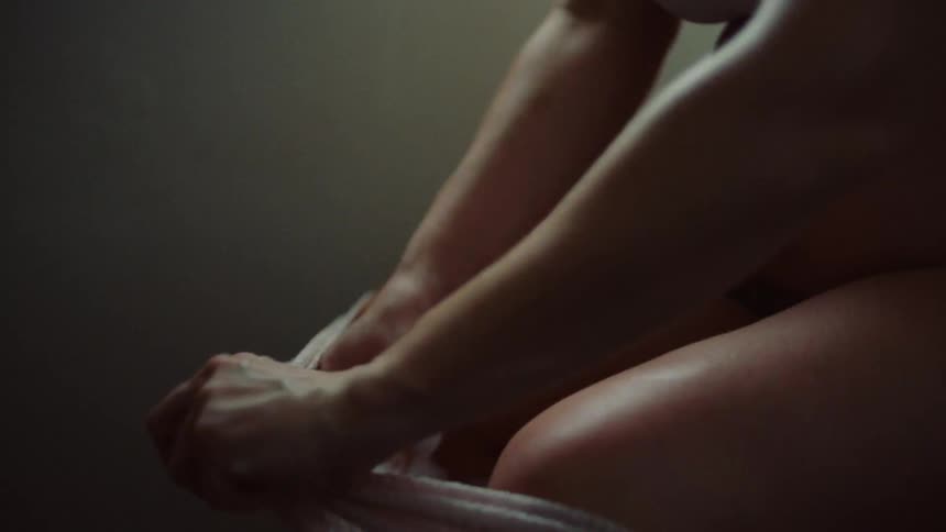 Closeup of a pregnant womans belly as she attaches a sanitary pad to her panties